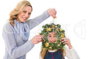 Festive mother and daughter holding christmas wreath