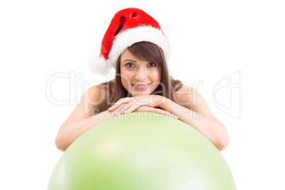 Festive fit brunette leaning on exercise ball