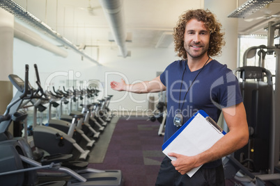 Smiling handsome trainer with clipboard in gym