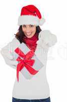 Excited brunette in santa hat giving gift