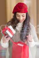 Happy brunette holding gift and looking in gift bag