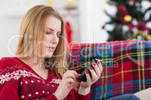 Pretty blonde sitting on the couch texting on the phone