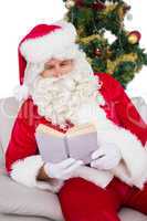 Relaxed santa reading on the couch