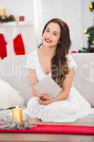 Smiling brunette on the couch reading letter at christmas