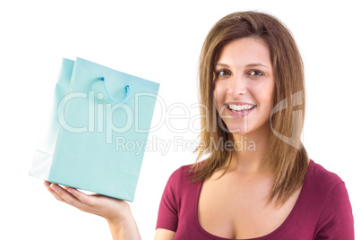 Brunette holding a gift bag smiling at camera