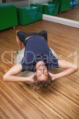 Man doing abdominal crunches on fitness ball in gym