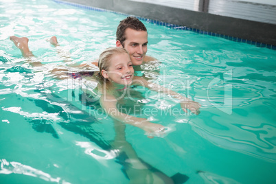 Cute little girl learning to swim with coach