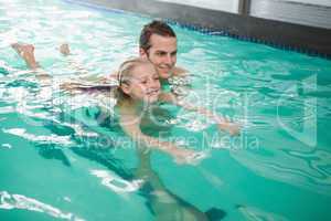 Cute little girl learning to swim with coach