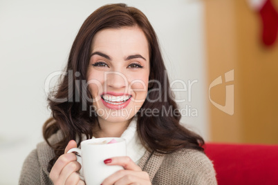 Smiling brunette enjoying a hot chocolate with marshmallow