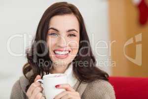 Smiling brunette enjoying a hot chocolate with marshmallow