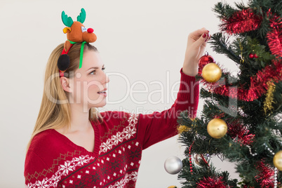 Woman hanging christmas decorations on tree