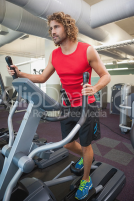 Determined man working out on x-trainer in gym