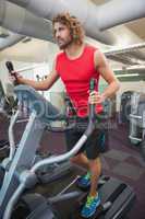 Determined man working out on x-trainer in gym