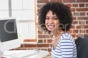 Smiling female photo editor using computer in office