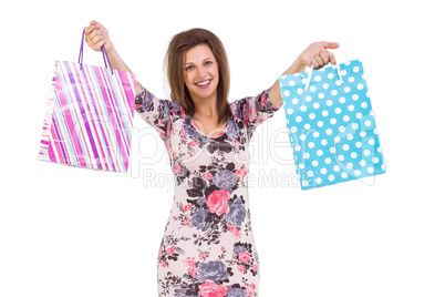 Young woman in floral dress holding up shopping bags