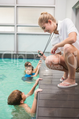 Pretty swimming coach showing boy his time