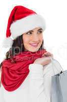 Smiling brunette in santa hat holding shopping bag