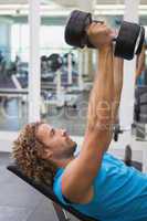 Side view of man exercising with dumbbells in gym