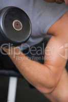 Close up mid section of man exercising with dumbbell
