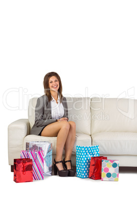 Smiling young woman sitting on couch with shopping bags