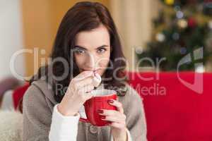 Brunette holding mug and eating marshmallow at christmas