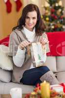 Brunette opening a gift on the couch at christmas