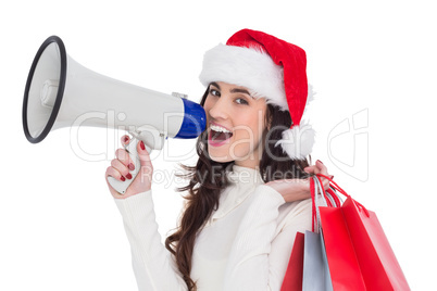 Festive brunette holding gift bags and megaphone