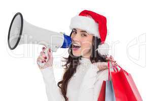 Festive brunette holding gift bags and megaphone