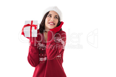 Surprised brunette in santa hat holding gift