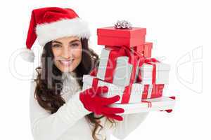 Festive brunette in santa hat holding pile of gifts