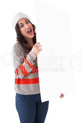 Excited brunette in santa hat showing white poster