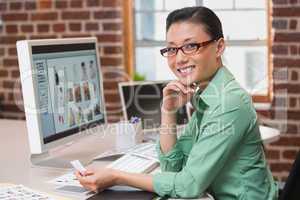 Smiling female photo editor using computer in office