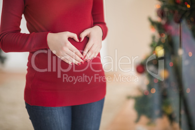 Close up of a pregnant woman making a heart on her belly