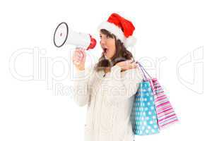 Festive brunette holding megaphone and bags