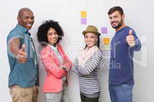 Team gesturing thumbs up at office