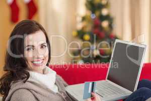 Brunette shopping online with laptop at christmas