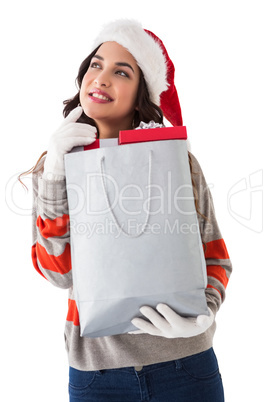 Thoughtful brunette holding shopping bag full of gifts