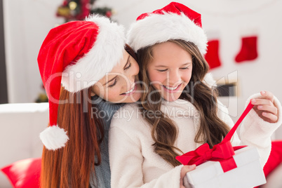 Festive mother and daughter on the couch with gift