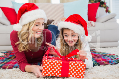 Festive little girl opening a gift with mother