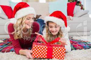 Festive little girl opening a gift with mother