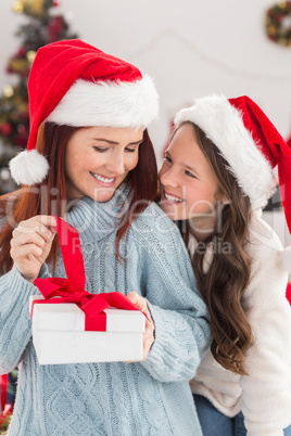 Festive mother and daughter on the couch with gift