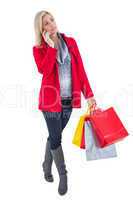 Happy blonde in winter clothes holding shopping bags