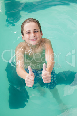 Little boy showing thumbs up in the pool