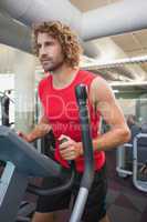 Determined man working out on x-trainer in gym