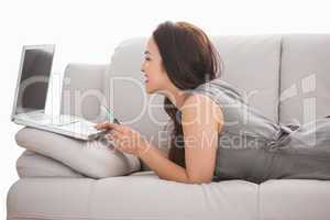 Beauty brunette using her laptop on the couch