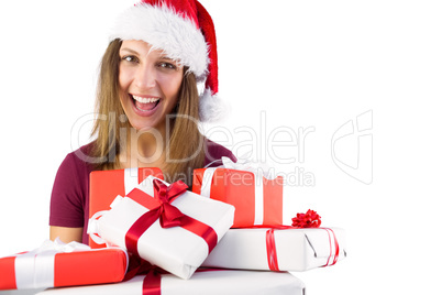 Smiling brunette in santa hat holding pile of gifts
