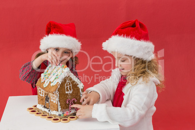 Festive little girls making a gingerbread house