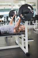 Young muscular man lifting barbell in gym