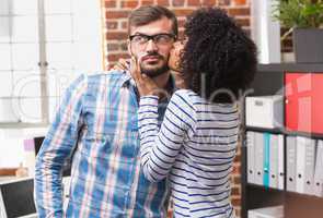 Young woman kissing man in office