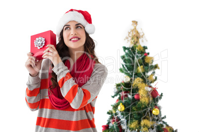 Festive brunette listening gift by the christmas tree